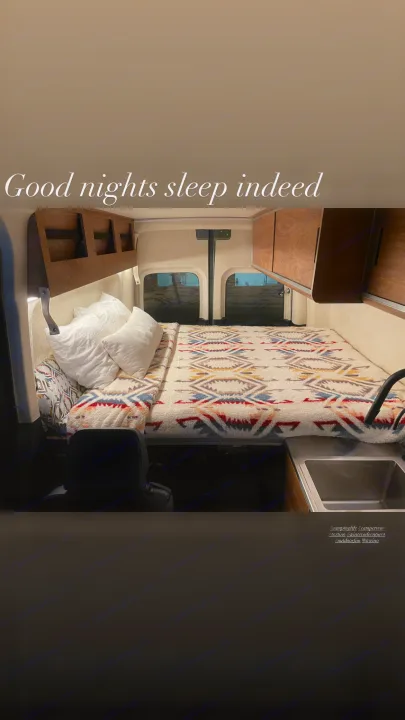 Cozy RV rental interior with a comfy bed, sink, & wood cabinets. Perfect for restful van life adventures!. Mercedes-Benz Sprinter “144” 2020