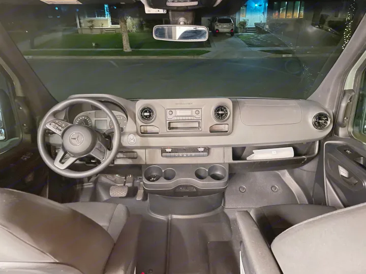 Nighttime view from an RV rental, showing the Mercedes-Benz Sprinter's dashboard, steering wheel, and street outside.. Mercedes-Benz Sprinter “144” 2020