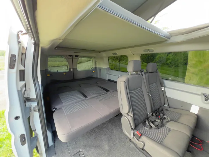 Spacious RV rental interior: rear seats convert to a bed, with an open pop-top roof. Enjoy versatile camper van travel.. Ford transit 2016
