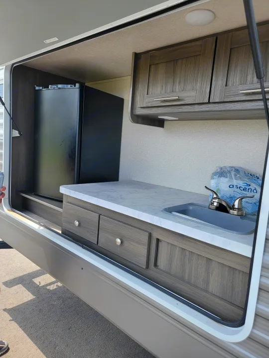 RV rental's compact pop-out kitchen features a sink, cabinets, and small refrigerator for convenient travel.. Forest River Shasta 2019