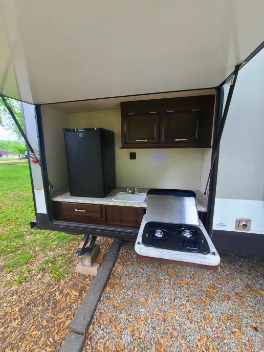 This RV rental's outdoor kitchen features a fridge, sink, and a two-burner stove for convenient camping meals.. Jayco Jay Flight 2020