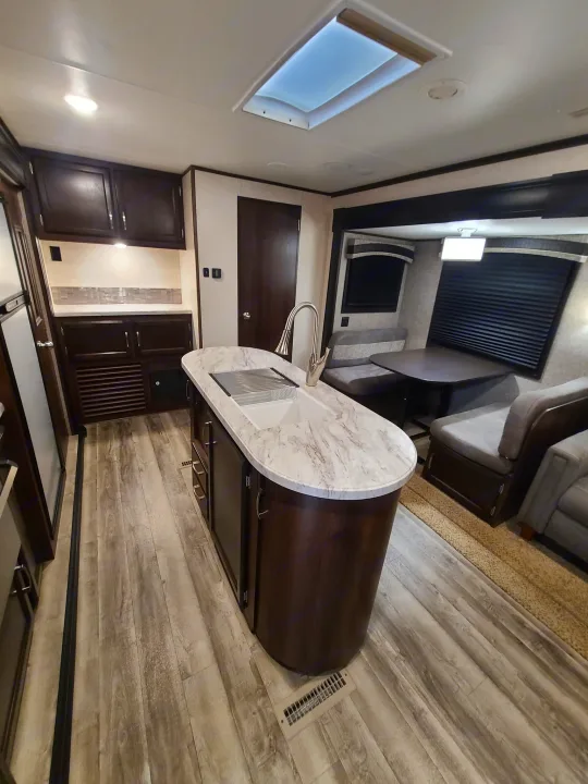 Modern RV rental interior: kitchen island, dining booth, and cozy living space with wood-look flooring.. Jayco Jay Flight 2020