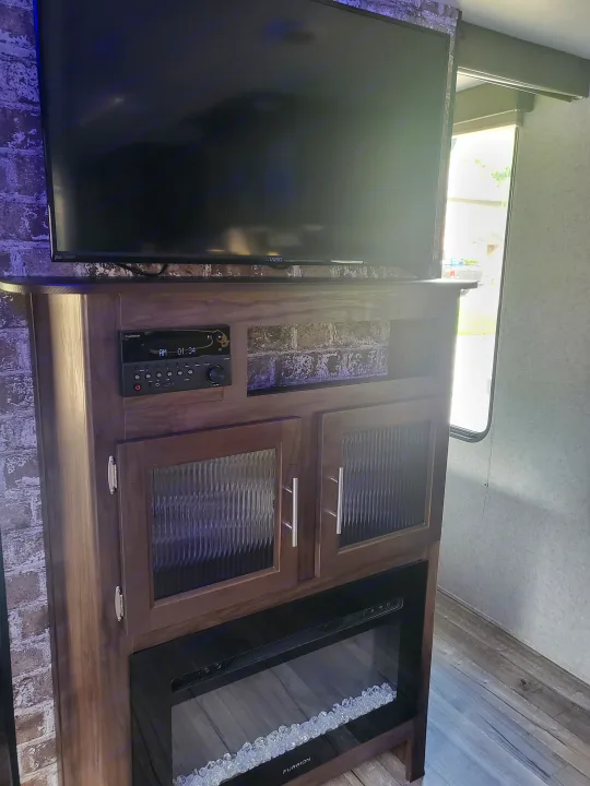 Inside an RV rental: a modern entertainment center featuring a TV, Furrion unit, and electric fireplace with faux crystals.. Forest River Cherokee Grey Wolf 2018