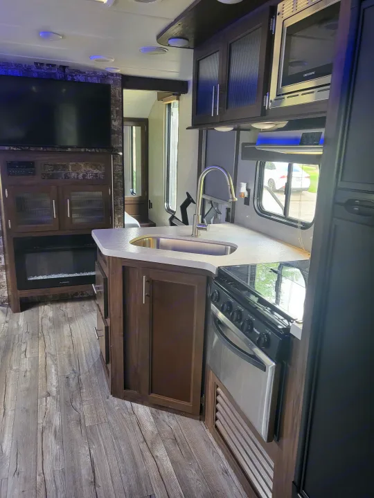 RV rental interior: modern kitchen with microwave, stove, sink, cabinets, and a comfortable living area.. Forest River Cherokee Grey Wolf 2018