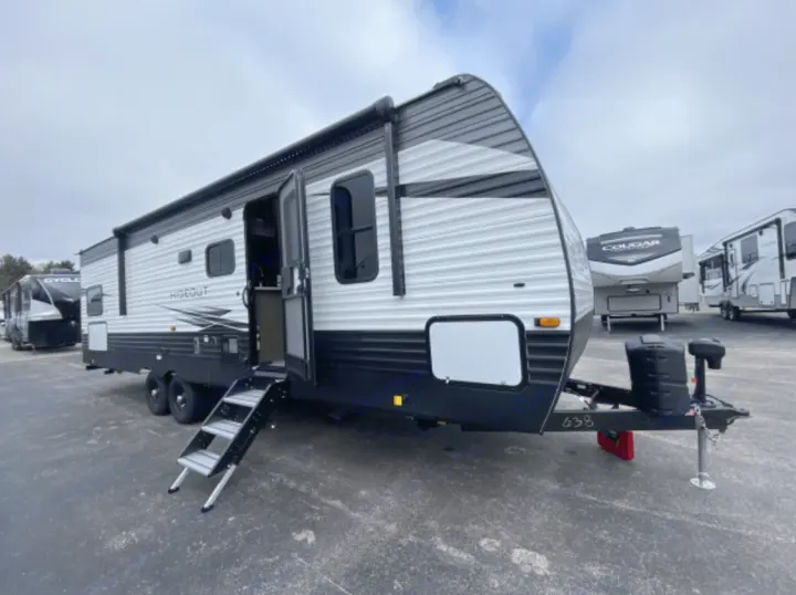 Explore the outdoors! This sleek white and black travel trailer, ideal for rv rental, features an open door with steps.. Keystone RV Hideout 2020