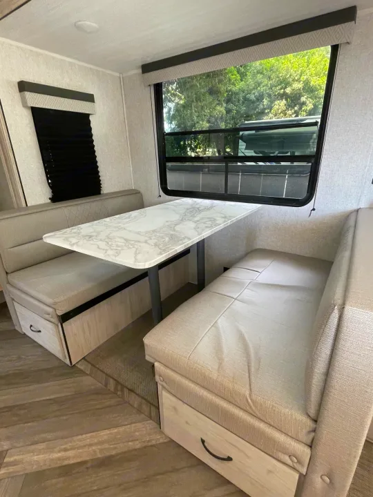 Comfortable RV rental dinette featuring plush benches, a marble-patterned table, and scenic window views.. East to West Other 2022