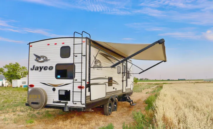 Jayco RV with awning extended, parked by a golden field under a blue sky. Ideal for your next rv rental trip.. Jayco Jay Flight SLX 2018