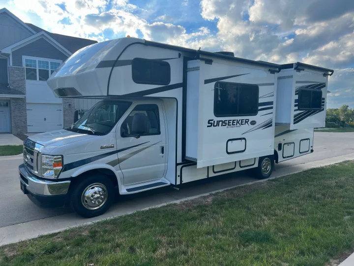 White Ford E-450 Class C RV rental, a Sunseeker by Forest River, parked on a driveway with slide-outs extended.. Forest River Sunseeker 2023