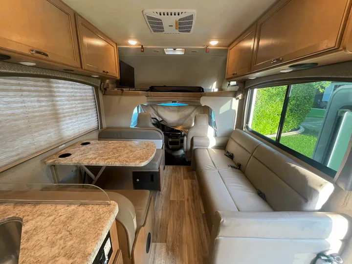 Spacious RV rental interior with dinette, sofa, and overhead bunk, ideal for comfortable travel.. Thor Four Winds 2021