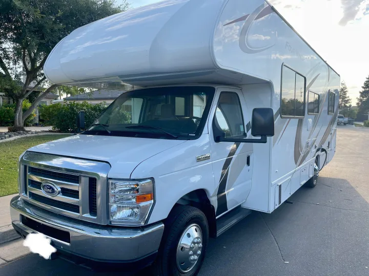 This white Four Winds Class C RV, a Ford E450 rv rental, is parked ready for travel.. Thor Four Winds 2021