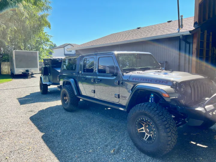 Modified grey Jeep Gladiator towing an off-road camping trailer, with another trailer nearby. Ideal setup for an RV rental adventure!. Vorsheer Vorsheer Trailer 2022