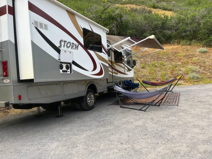 This RV rental is perfectly set up for relaxation at a sunny campsite, featuring an extended awning and two inviting hammocks with stands.. Fleetwood Storm 32BH 2013