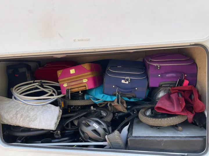RV rental's packed storage bay with colorful luggage, folded bikes, and road trip essentials.. Thor Four Winds 2019