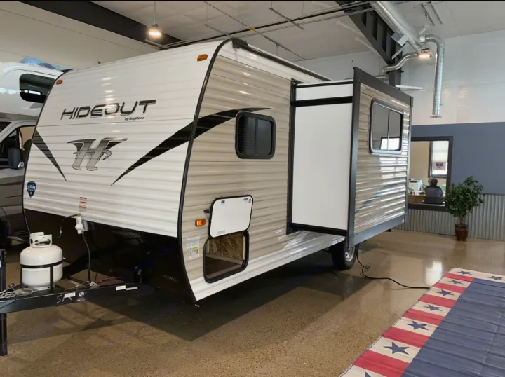 This new Hideout travel trailer, ideal for RV rental & camping, is shown indoors with its slide-out extended.. Keystone RV Hideout 2019