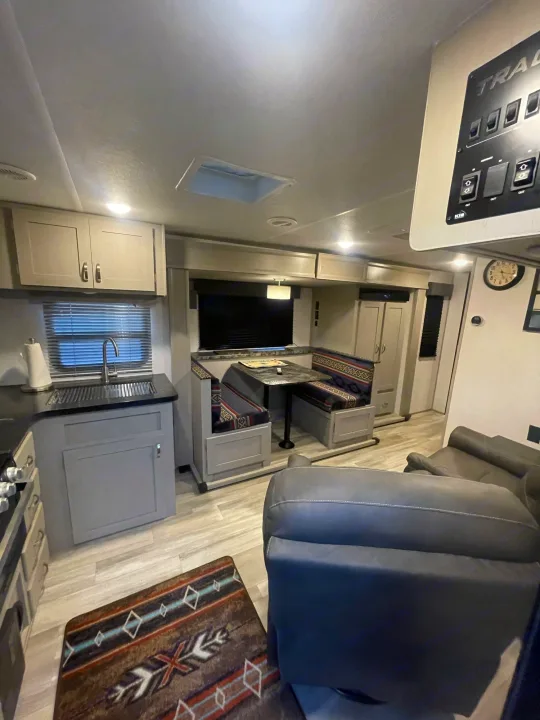 RV rental interior featuring a well-appointed kitchen sink area, dinette with patterned cushions, and cozy living space with recliners.. Prime Time Tracer 2021