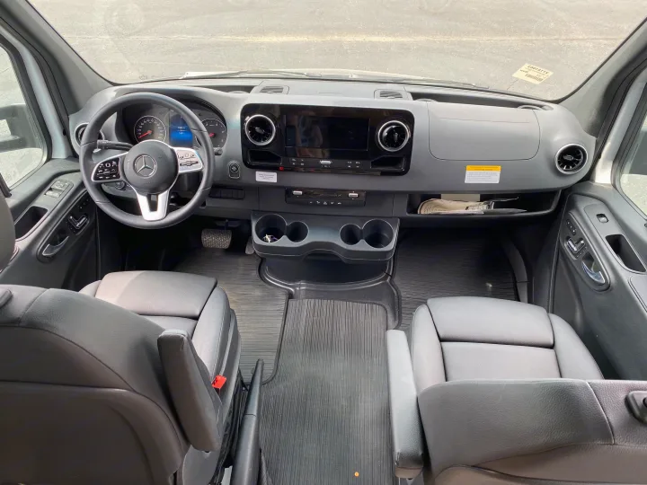 Spacious Mercedes RV rental cockpit showing dashboard, steering wheel, and front seats, ready for a journey.. Tiffin Motorhomes Wayfarer LW 2023