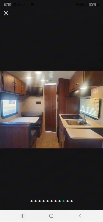 Inside an RV rental: a cozy dinette, well-equipped kitchen with sink & stovetop, and mounted TV. Ideal for comfortable travel.. Forest River Rockwood Geo Pro 2018