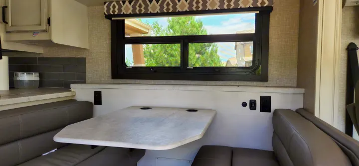 RV rental dinette interior: booth seating, table, window view, and convenient power outlets on the wall for your travels.. Jayco Alante 2021