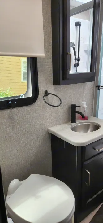 RV rental bathroom: a modern shower, sink, toilet, and window. Black fixtures and gray textured walls.. Jayco Alante 2021