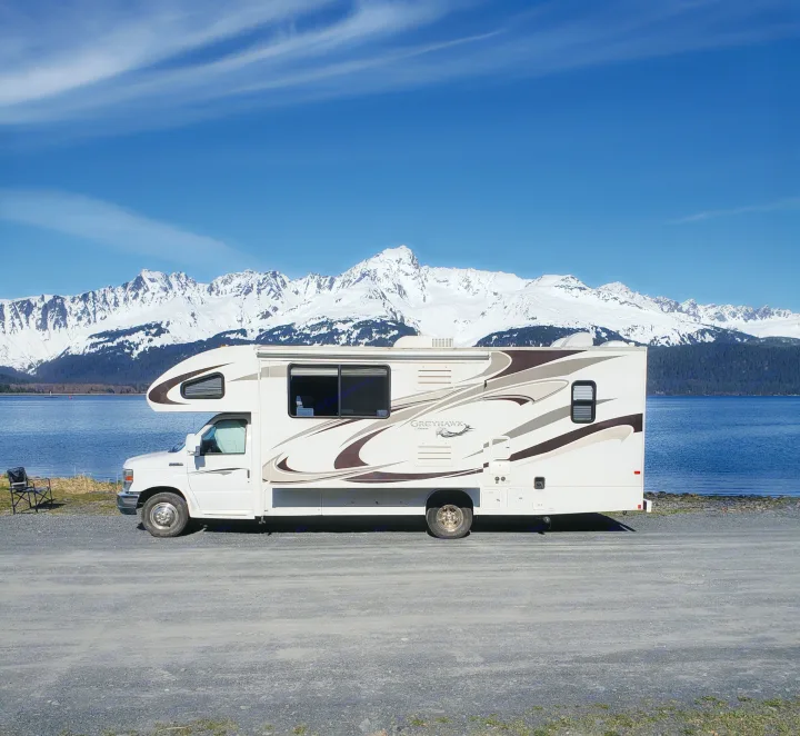 Scenic Greyhawk RV rental by a tranquil lake, framed by majestic snow-capped mountains under a clear blue sky.. Jayco Greyhawk 2011