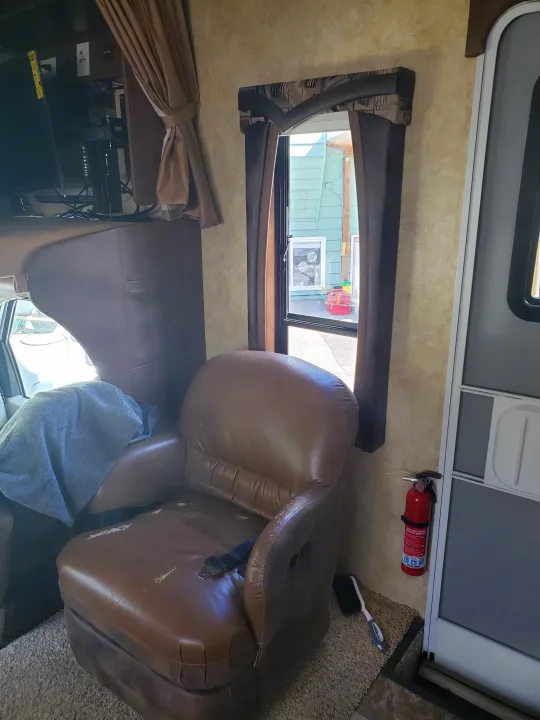 RV rental: view of the interior showing a brown armchair, TV, window, and a fire extinguisher mounted by the door.. Jayco Greyhawk 2011