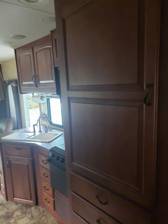 Inside an RV rental: a kitchen featuring a sink, stove, and rich wood cabinets. Ready for your travels!. Jayco Greyhawk 2011