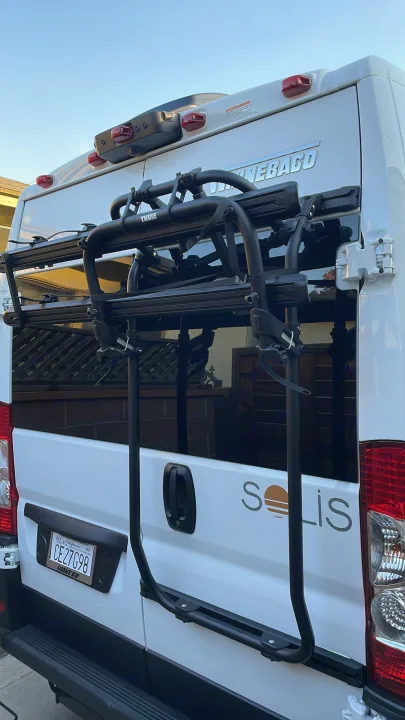 Rear of a white Winnebago Solis RV rental, featuring a Thule bike rack, backup camera, and California 'Giant RV' plate.. Winnebago Winnebago 2023