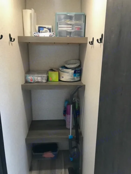 Efficient RV rental storage showing paper products, cleaning supplies, and organized essentials in a compact space.. KZ Sportsmen LE 2021