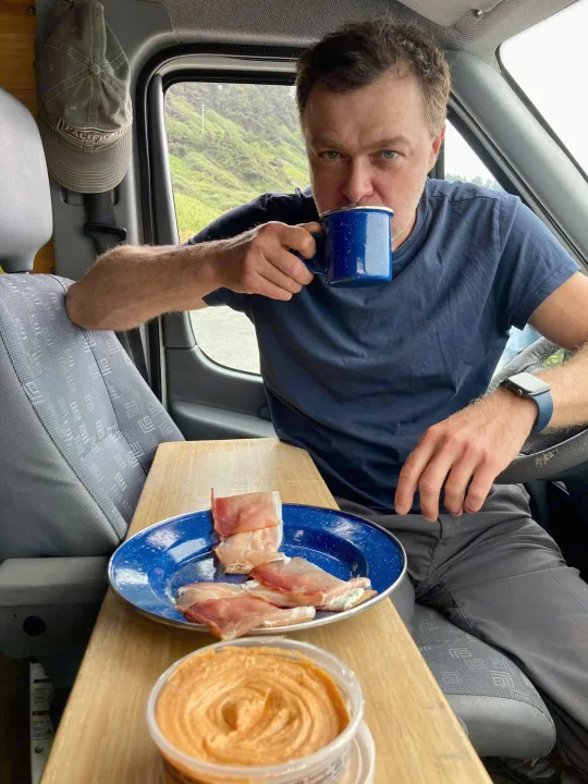 Man enjoying coffee & prosciutto in his rv rental, a perfect van life breakfast with a view.. Mercedes Sprinter 2006