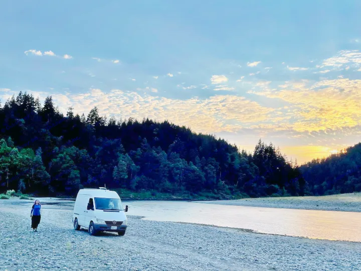 Experience serene nature camping with an RV rental. White van, person, and river at golden hour.. Mercedes Sprinter 2006