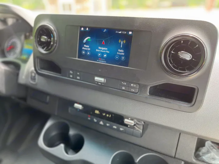 Modern rv rental dashboard featuring an infotainment screen with navigation, phone, and SiriusXM radio, plus climate controls.. Mercedes Sprinter Motorhome Campervan RV 2021