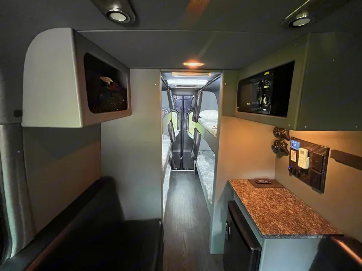 RV rental interior: narrow aisle, twin bunk beds at rear, microwave, mini-fridge, and comfortable seating.. Mercedes Sprinter Motorhome Campervan RV 2021