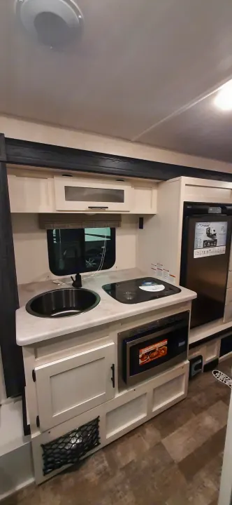 Compact RV rental kitchen: modern sink, microwave, refrigerator, and cabinet storage.. Forest River RPOD 190 2021