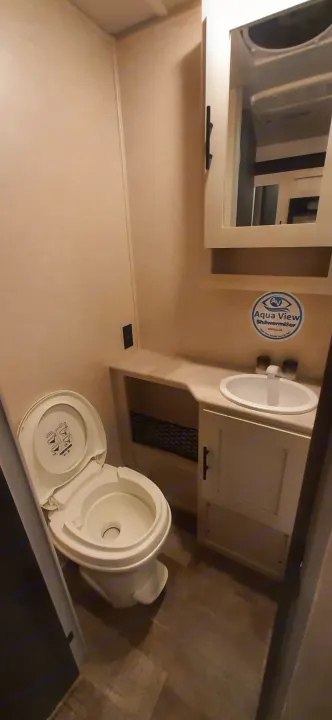 Clean RV rental bathroom featuring a toilet, sink, and mirror. An Aqua View ShowerMiser system is visible for water efficiency.. Forest River RPOD 190 2021
