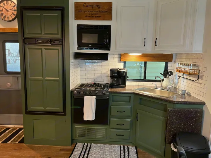 Cozy RV rental kitchen design: deep green lower cabinets, white uppers, black appliances, and subway tile backsplash.. Heartland RVs Greystone 2012