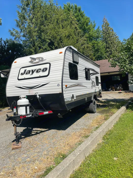 A white and black Jayco travel trailer, perfect for your next RV rental adventure, parked on a sunny gravel driveway.. Jayco Jay Flight SLX 2016