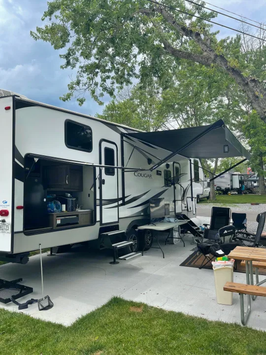 This white RV rental (Cougar travel trailer) features an open outdoor kitchen and extended awning, perfect for a camp site setup.. Keystone RV Cougar 32BHS 2021
