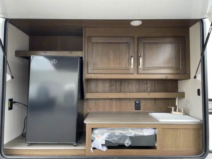 RV rental: Enjoy the convenience of this outdoor kitchen, featuring a mini-fridge, sink, cabinets, and pull-out grill.. Keystone RV Cougar 32BHS 2021