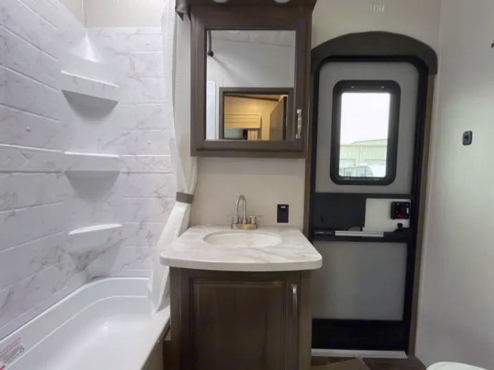Clean RV rental bathroom with a full tub/shower, vanity, sink, and interior exit door. Perfect for comfortable travels.. Keystone RV Cougar 32BHS 2021