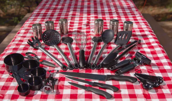 Various cooking utensils & measuring tools on a red checkered table, perfect for an RV rental outdoor kitchen.. Braxton Creek Free Solo 2022