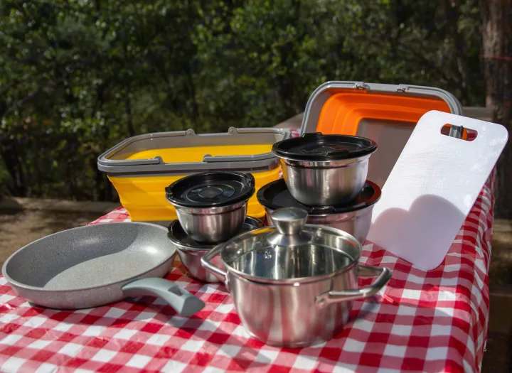 RV rental ready! Essential camping cooking gear: pans, pots, bowls, and collapsible bins on a picnic table for outdoor meals.. Braxton Creek Free Solo 2022