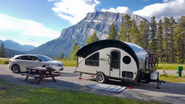 RV rental adventure: Car and sleek Alto travel trailer with bikes at a scenic mountain campsite with picnic table.. Safari Condo Alto R1723 Bunkhouse 2022