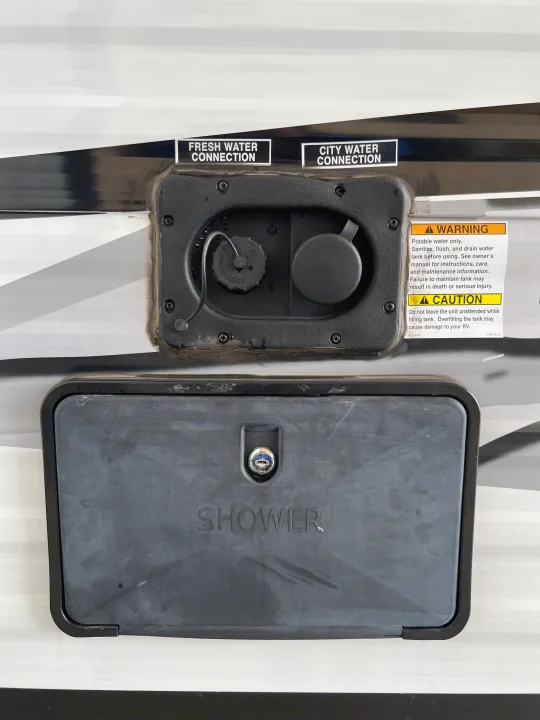 An RV rental's water hookups: fresh water, city water, and outdoor shower, with important tank filling warnings.. Dream 290DBS 2022