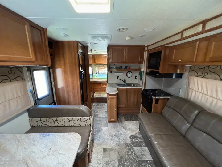 Spacious RV rental interior featuring a full kitchen, comfortable dining booth, and cozy living area.. Coachmen Leprechaun 2019