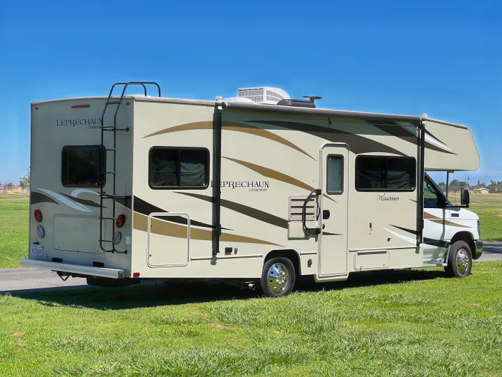 Spacious Coachmen Leprechaun Class C motorhome RV, ideal for your next rv rental adventure. Parked on green grass under a clear blue sky.. Coachmen Leprechaun 2019