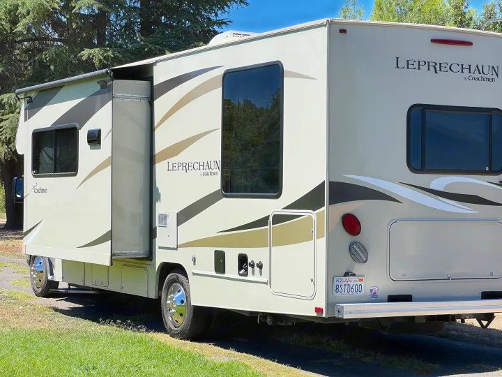 A light-colored Coachmen Leprechaun RV rental with an extended slide-out, parked outdoors for your next adventure.. Coachmen Leprechaun 2019
