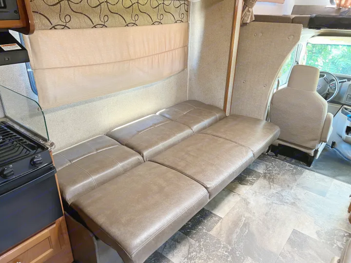 This RV rental's interior features comfortable brown bench seating that converts to a bed, a kitchen area, and the driver's cab.. Coachmen Leprechaun 2019