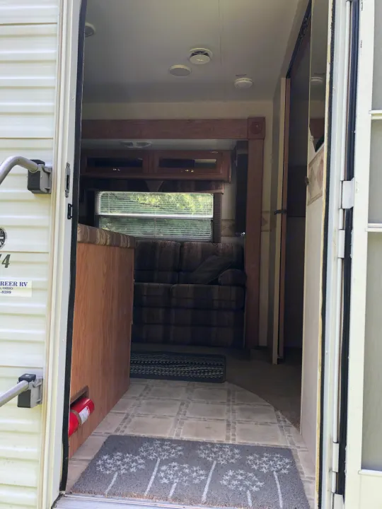 View inside an RV rental from the open door, showcasing a living area with a sofa, window, tiled floor, and a visible fire extinguisher.. Jayco Eagle 2003
