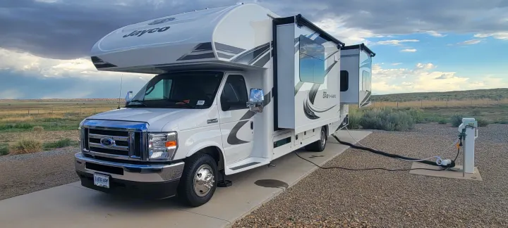 White Jayco Greyhawk rv rental Class C motorhome parked with slide-outs extended & connected to campsite utilities.. Jayco Greyhawk 2021