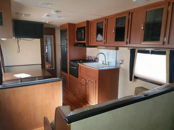 Inside a comfortable rv rental: kitchen with stove, sink, fridge; dinette; and living room with TV.. Forest River Salem 2016